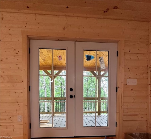 doorway to outside with wood walls, french doors, and a healthy amount of sunlight