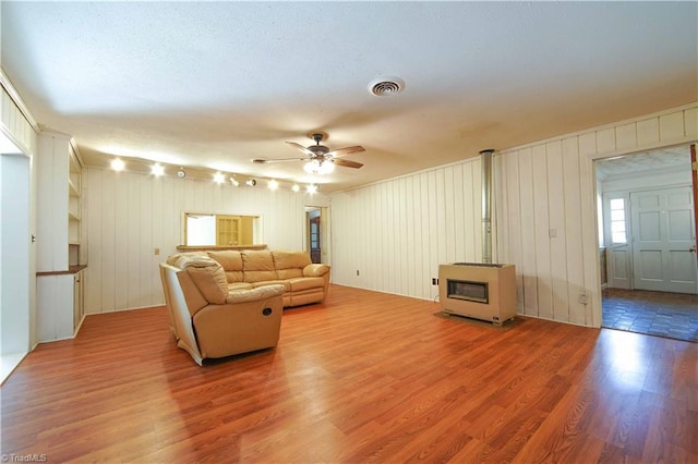 living room with hardwood / wood-style floors, a textured ceiling, ceiling fan, and wooden walls