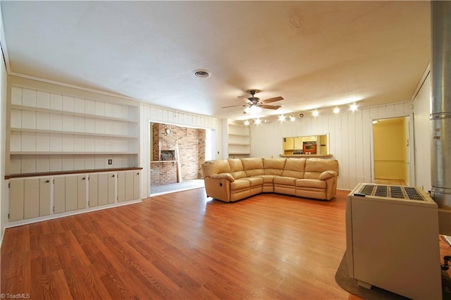 living room with built in shelves, ceiling fan, light hardwood / wood-style floors, and ornamental molding