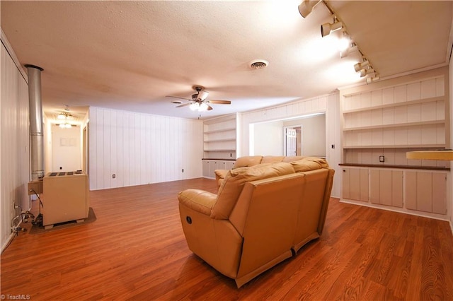 living room featuring ceiling fan, hardwood / wood-style floors, rail lighting, and a textured ceiling