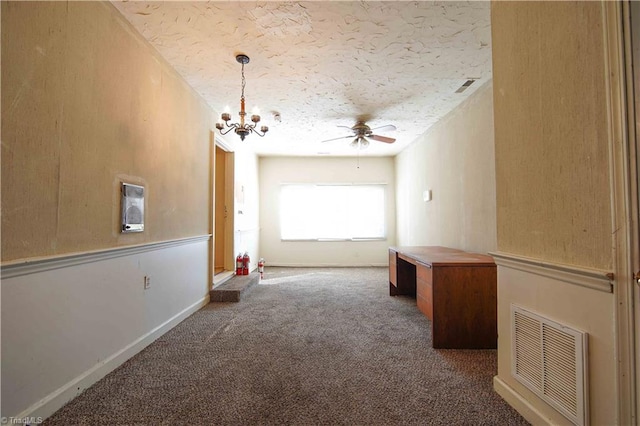 carpeted spare room featuring ceiling fan with notable chandelier and a textured ceiling