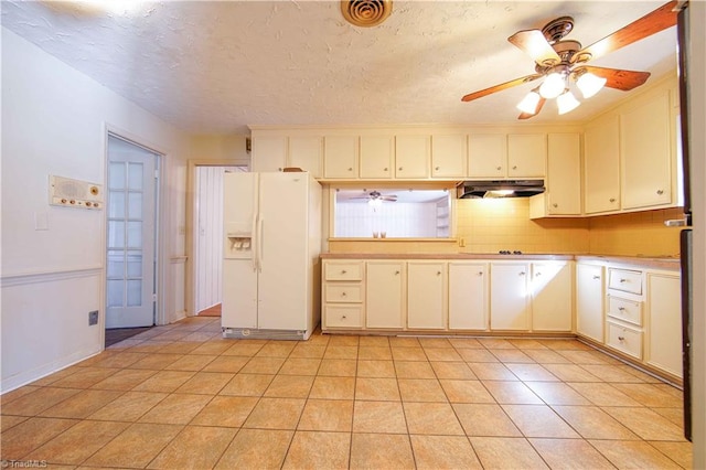 kitchen with ceiling fan, white fridge with ice dispenser, a textured ceiling, decorative backsplash, and light tile patterned floors