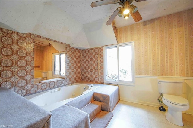 bathroom featuring a tub to relax in, ceiling fan, and toilet