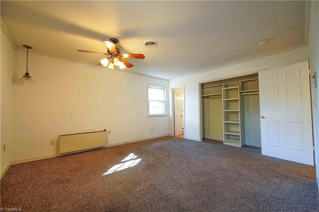 unfurnished bedroom featuring ceiling fan, a closet, and dark carpet