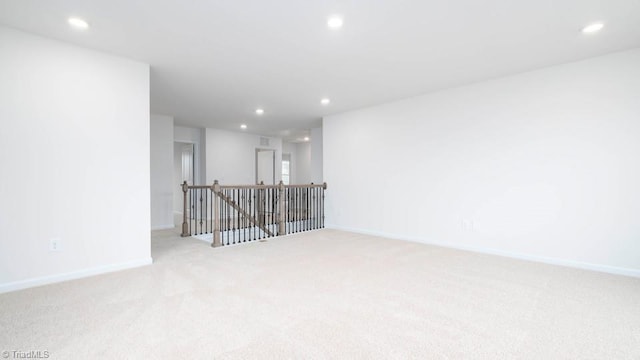 unfurnished room with recessed lighting, baseboards, and light carpet