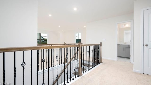 hallway featuring baseboards, an upstairs landing, carpet flooring, recessed lighting, and a sink