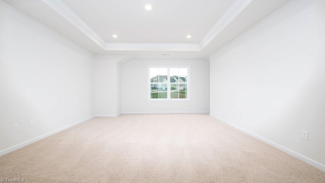 spare room with recessed lighting, baseboards, a tray ceiling, and ornamental molding