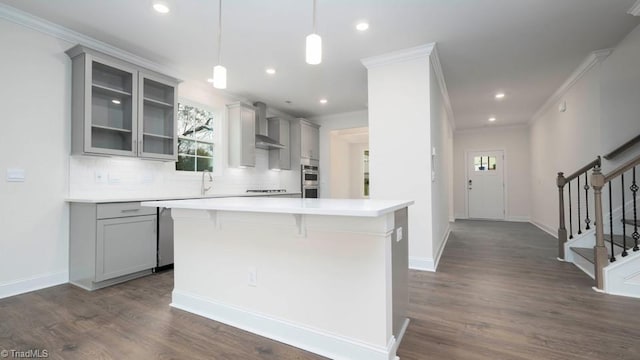 kitchen featuring crown molding, wall chimney exhaust hood, light countertops, and gray cabinets