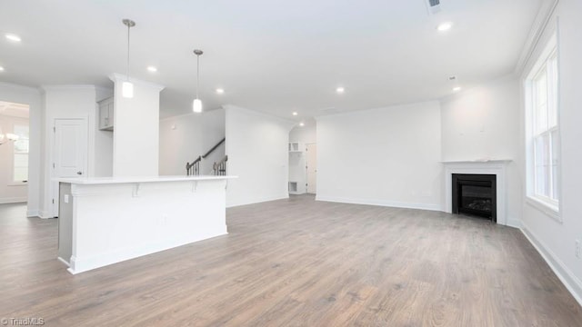 unfurnished living room featuring stairway, ornamental molding, recessed lighting, a fireplace, and wood finished floors