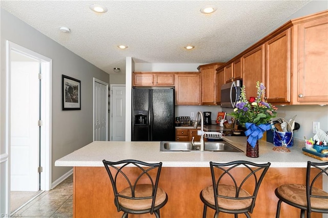 3714 Courtland Cir, Thomasville, NC 27360 - kitchen featuring black fridge, stainless steel microwave, a peninsula, brown cabinetry, and light countertops
