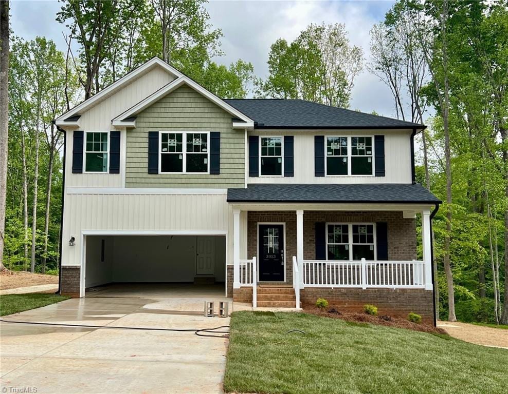 craftsman-style house featuring an attached garage, a front yard, a shingled roof, concrete driveway, and a porch
