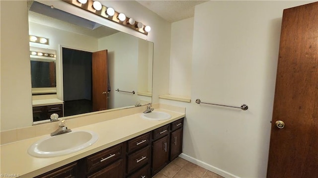 bathroom with double vanity, baseboards, tile patterned floors, and a sink