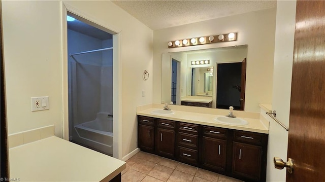 full bathroom with washtub / shower combination, double vanity, a sink, a textured ceiling, and tile patterned floors