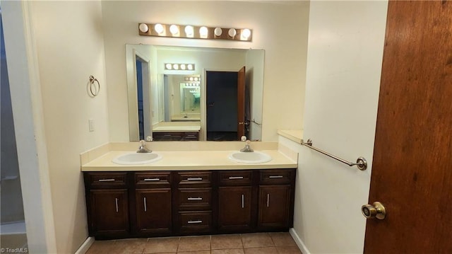 full bathroom featuring double vanity, tile patterned floors, baseboards, and a sink