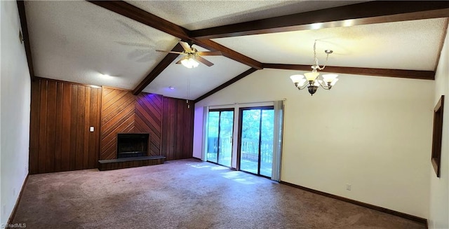 unfurnished living room with wood walls, a textured ceiling, a fireplace, carpet floors, and ceiling fan with notable chandelier