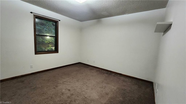 empty room with a textured ceiling, baseboards, and carpet floors