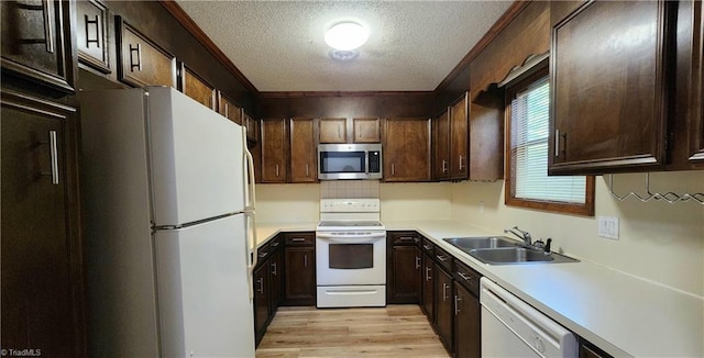 kitchen with light wood-type flooring, tasteful backsplash, white appliances, sink, and a textured ceiling