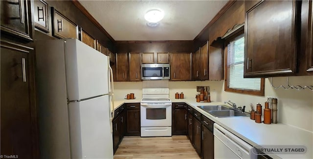 kitchen with dark brown cabinets, light wood-type flooring, light countertops, white appliances, and a sink