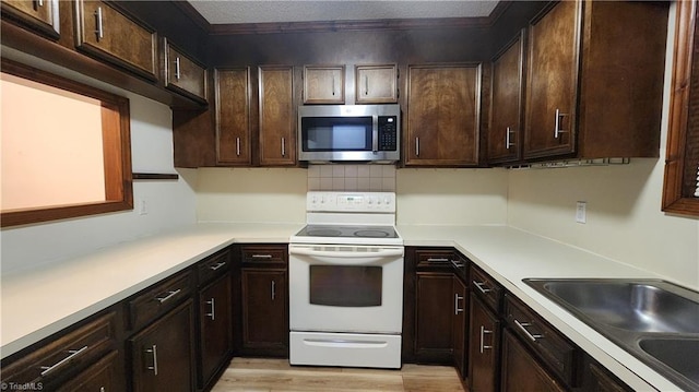 kitchen featuring dark brown cabinetry, stainless steel microwave, light countertops, and white electric range