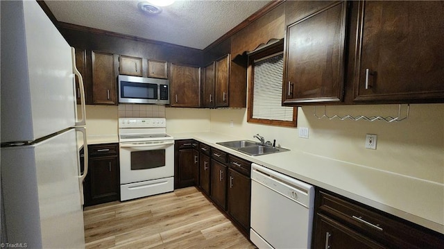 kitchen with a sink, a textured ceiling, white appliances, light wood-style floors, and dark brown cabinets