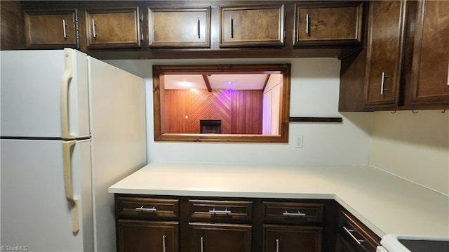 kitchen with dark brown cabinets, light countertops, and freestanding refrigerator