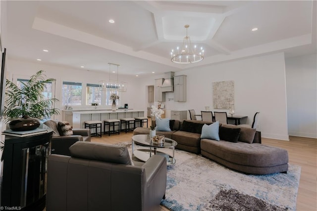 living room with coffered ceiling, a chandelier, beamed ceiling, and light hardwood / wood-style flooring