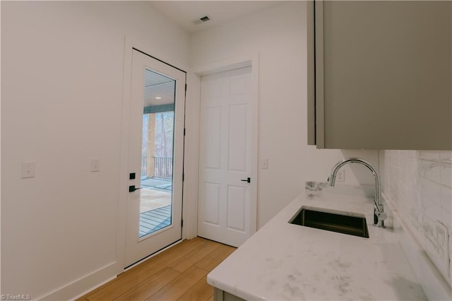 interior space featuring decorative backsplash, sink, and hardwood / wood-style flooring