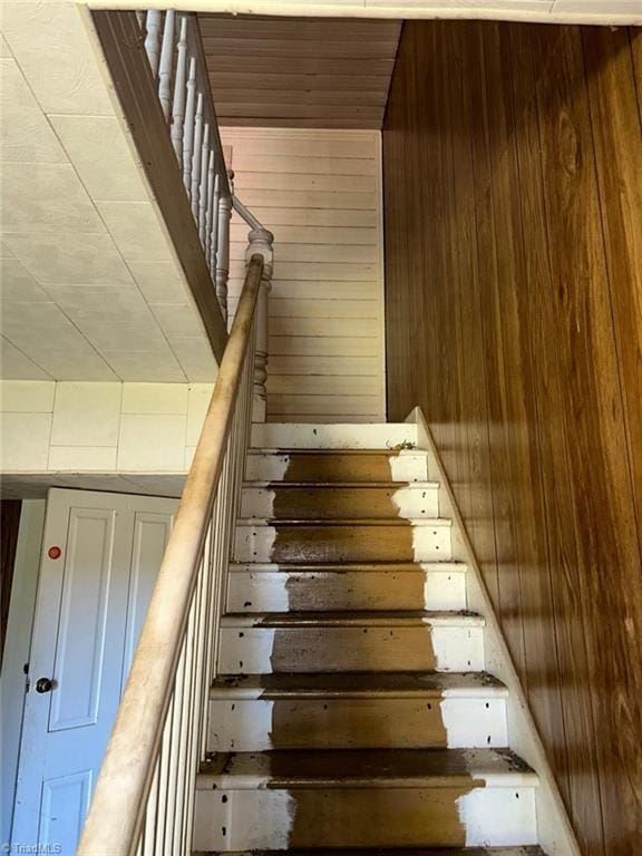 staircase featuring wooden walls