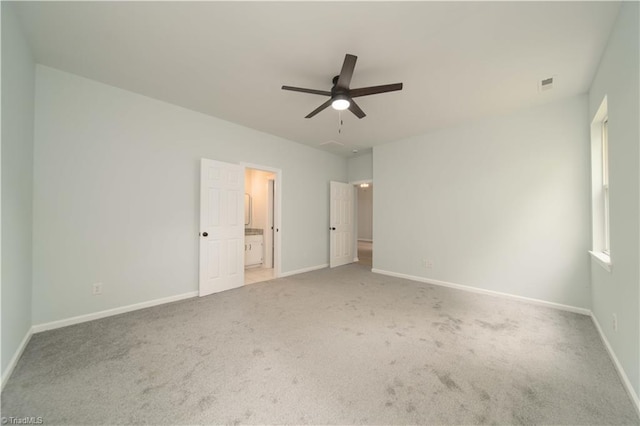 unfurnished bedroom featuring carpet floors, visible vents, baseboards, a ceiling fan, and ensuite bath