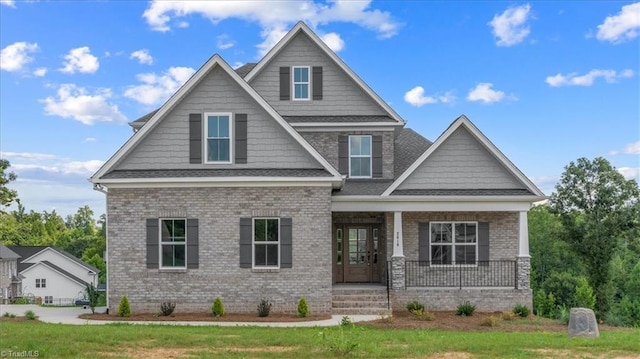 craftsman house featuring covered porch and brick siding