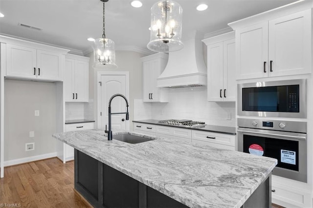 kitchen featuring custom range hood, appliances with stainless steel finishes, white cabinets, and a sink