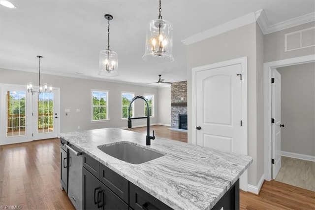 kitchen featuring a stone fireplace, a sink, visible vents, open floor plan, and ornamental molding