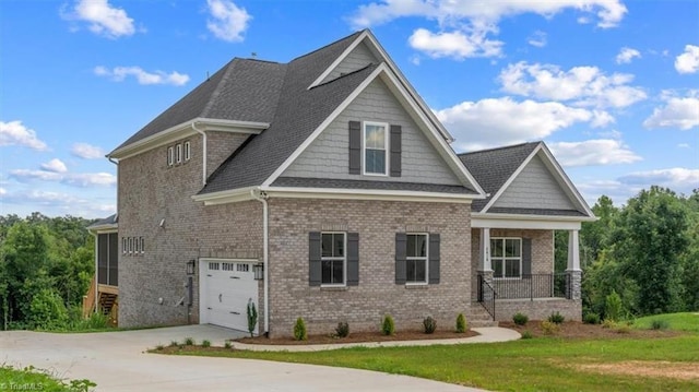 craftsman-style home with concrete driveway, an attached garage, a front lawn, a porch, and brick siding