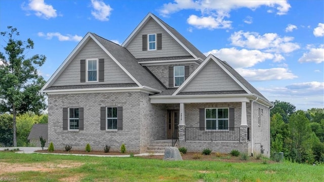 craftsman inspired home featuring covered porch, brick siding, and a front lawn