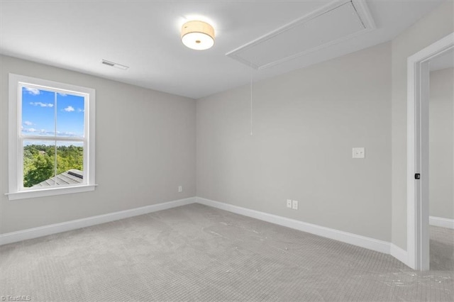 spare room with attic access, visible vents, carpet floors, and baseboards