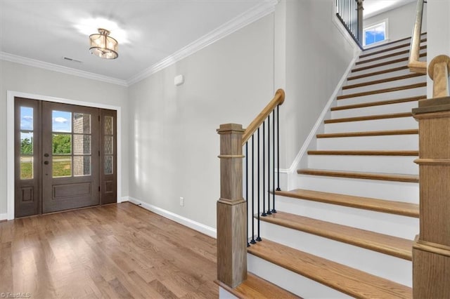 foyer entrance with crown molding, visible vents, stairway, wood finished floors, and baseboards