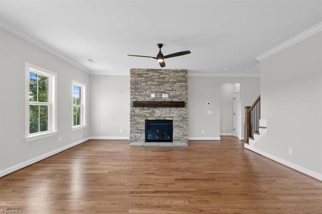 unfurnished living room featuring baseboards, a ceiling fan, stairway, wood finished floors, and a stone fireplace