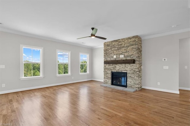 unfurnished living room featuring ornamental molding, wood finished floors, and a stone fireplace