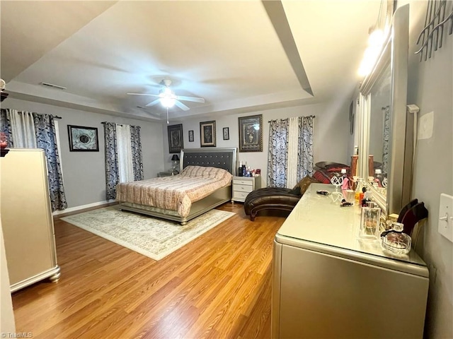 bedroom featuring a raised ceiling, ceiling fan, and hardwood / wood-style flooring