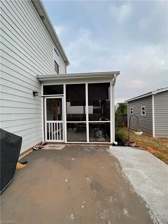 view of patio featuring a sunroom and an outbuilding