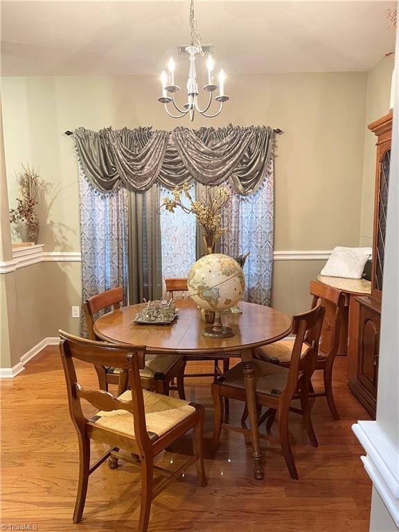 dining room featuring wood-type flooring and an inviting chandelier