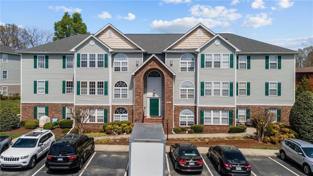 multi unit property with brick siding and uncovered parking