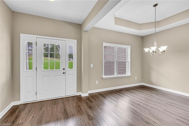 entrance foyer featuring a chandelier, baseboards, a raised ceiling, and wood finished floors