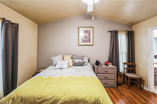 bedroom with ensuite bathroom, dark wood-type flooring, and vaulted ceiling