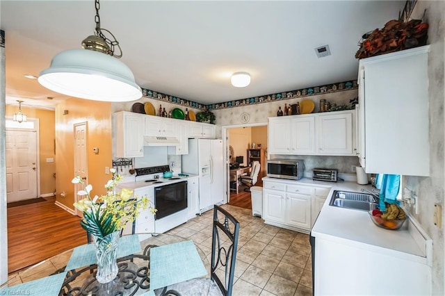 kitchen featuring white appliances, sink, white cabinets, hanging light fixtures, and light tile patterned flooring