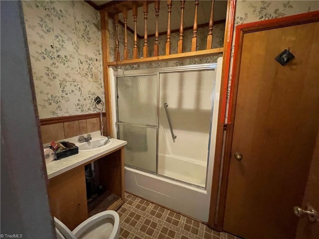 705 Washington St, Graham, NC 27253 - bathroom featuring wallpapered walls, wainscoting, bath / shower combo with glass door, vanity, and toilet