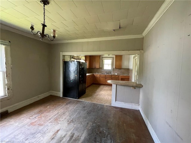705 Washington St, Graham, NC 27253 - kitchen with freestanding refrigerator, ornamental molding, brown cabinetry, wood finished floors, and a chandelier