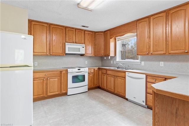 kitchen with white appliances, a textured ceiling, and sink