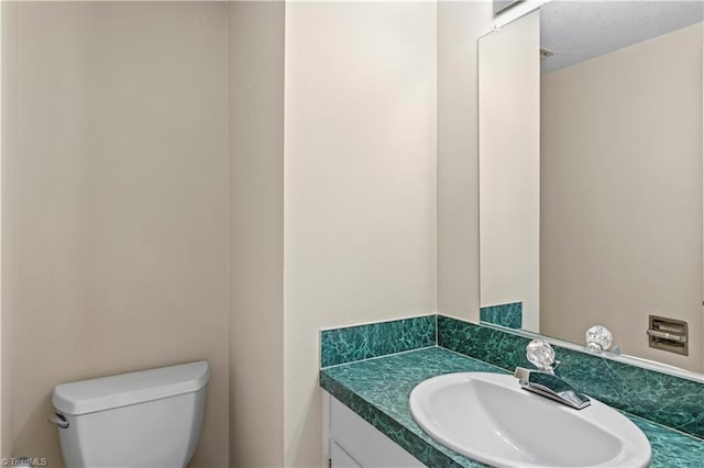 bathroom featuring toilet, vanity, and a textured ceiling