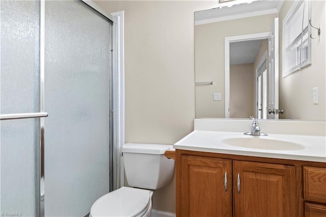 bathroom with a shower with shower door, vanity, toilet, and crown molding